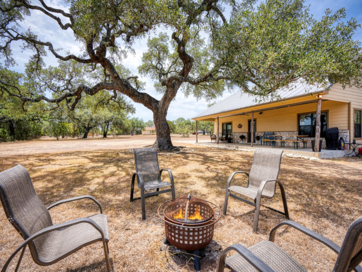View of front of house from Firepit seating area under beautiful oak tree.